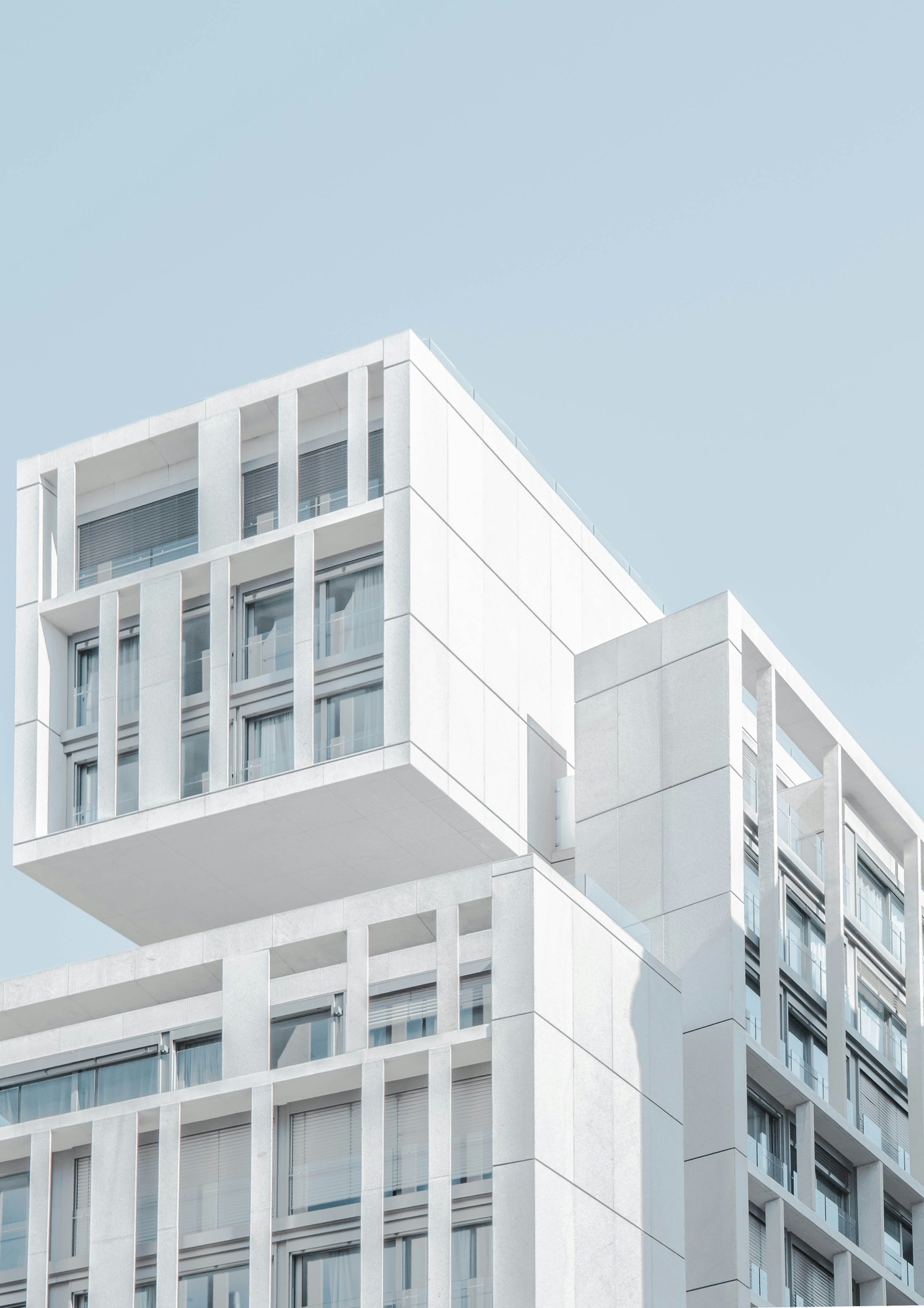 Facciata di un edificio residenziale moderno in cemento bianco, con volumi aggettanti