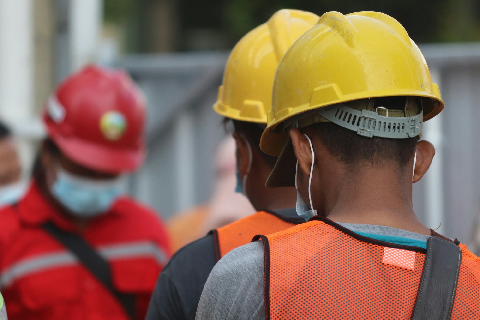 Operai in cantiere con casco giallo e gilet ad alta visibilità, dispositivi di protezione individuale
